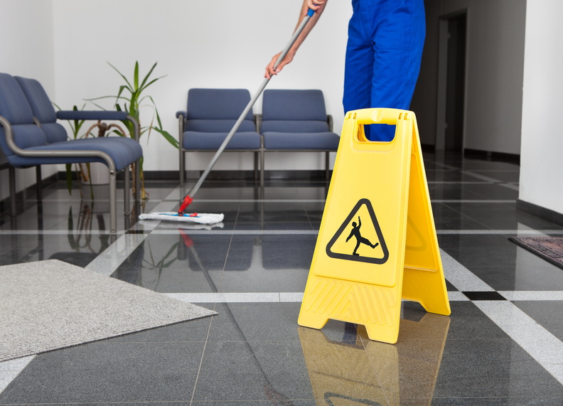 Close-up Of Man Cleaning The Floor With Yellow Wet Floor Sign